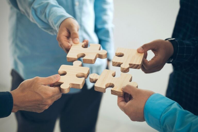 Konzept der Teamarbeit und Partnerschaft. Geschäftsleute fügen im Büro Puzzleteile zusammen. Geschäftsleute, die das Jigsaw-Team zusammensetzen. Wohltätigkeit, Freiwillige. Einigkeit, Team Business. Geschäftsidee.CSR.ESG